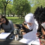 Tre studenti che studiano al parco in primavera