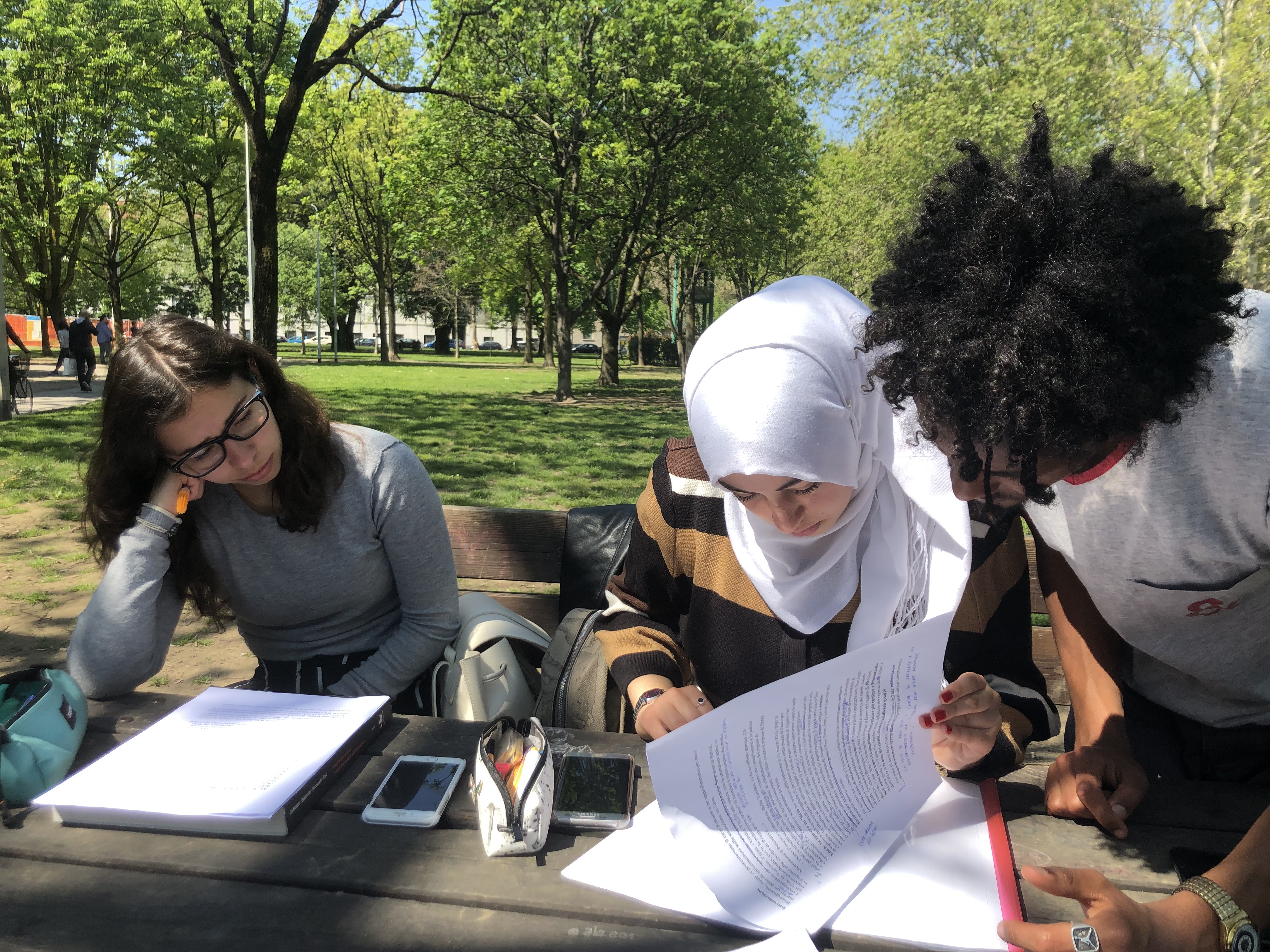 Tre studenti che studiano al parco in primavera